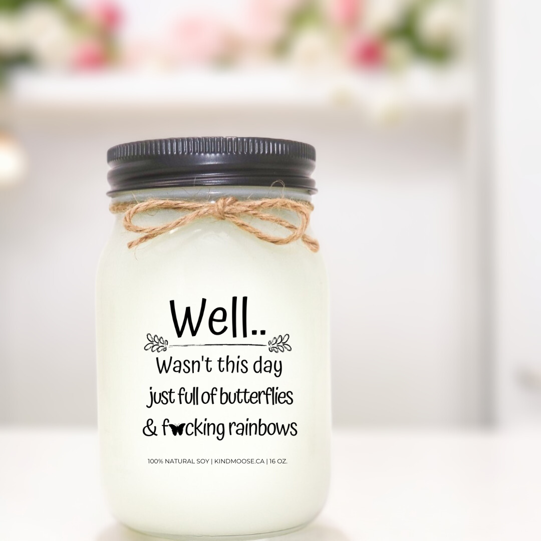 A 16 oz mason jar soy  candle with a label that says "Well..Wasn't this day just full of Butterflies & F*@king Rainbows."