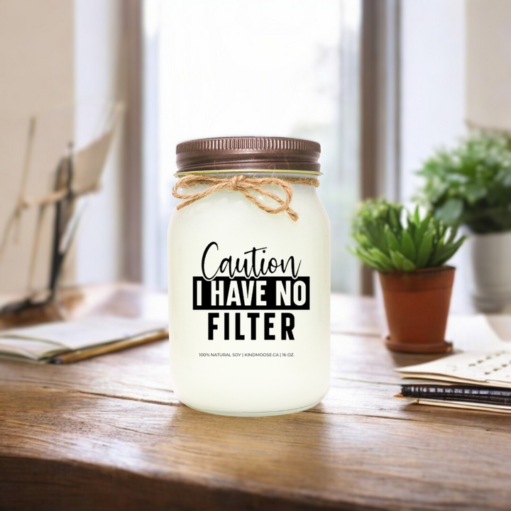 16 oz soy candle in a mason jar with twine bow, featuring the label 'Caution: I Have No Filter,' placed on a rustic wooden desk, Brown Lid