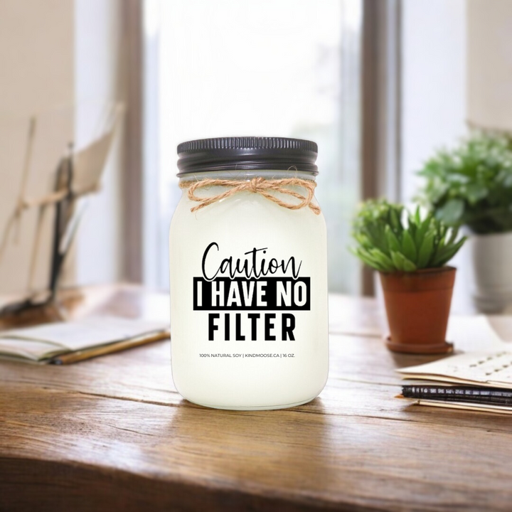 16 oz soy candle in a mason jar with twine bow, featuring the label 'Caution: I Have No Filter,' placed on a rustic wooden desk, Black Lid