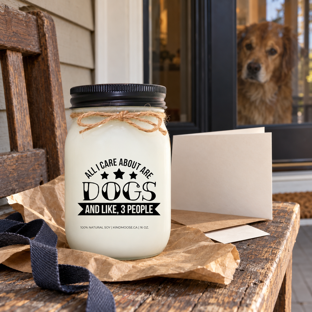 KINDMOOSE All I Care About Are Dogs and Like 3 People candle prepared as a personal gift on a front porch while a dog watches from inside.