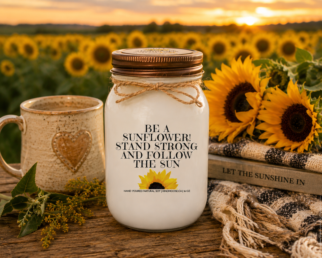 BE A SUNFLOWER! STAND STRONG AND FOLLOW THE SUN soy candle with distressed bronze lid styled in a sunflower field gathering scene with fresh blooms, countryside charm, and warm autumn sunshine.