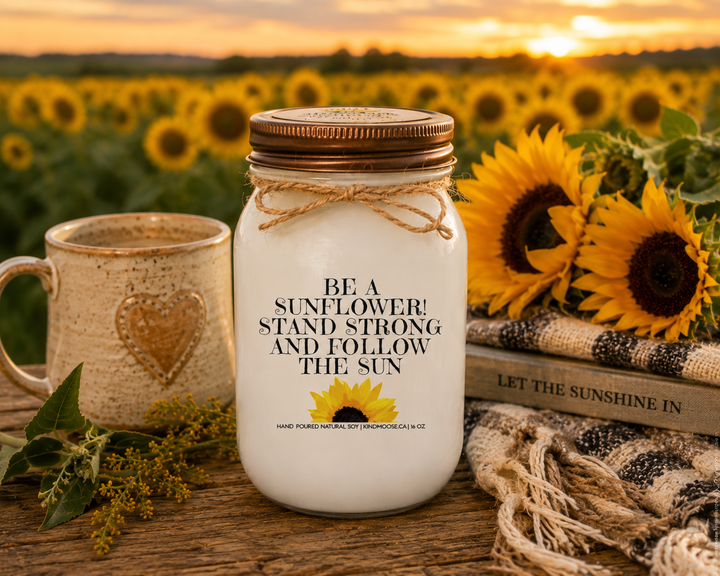 BE A SUNFLOWER! STAND STRONG AND FOLLOW THE SUN soy candle with distressed bronze lid styled in a sunflower field gathering scene with fresh blooms, countryside charm, and warm autumn sunshine.