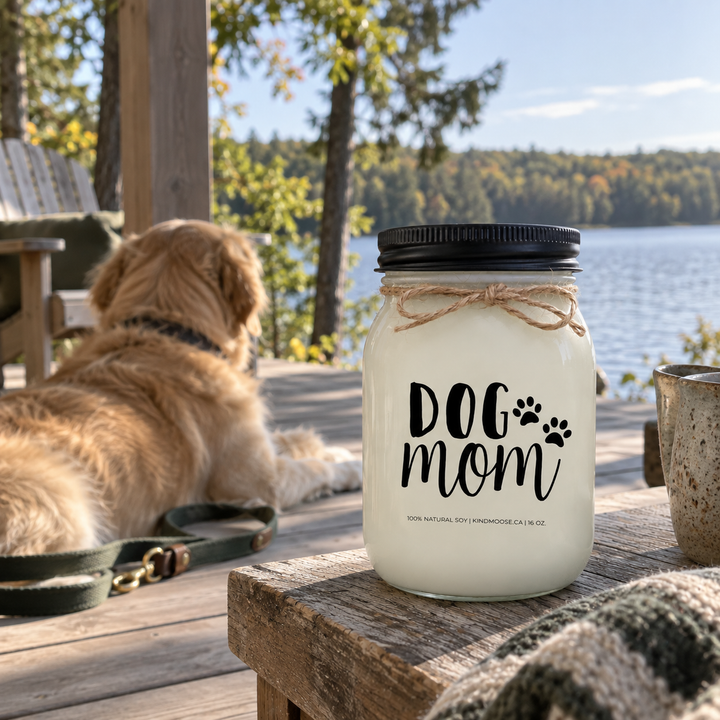 KINDMOOSE DOG MOM 16 oz candle on a lakeside cottage deck with an adult Golden Retriever nearby on a peaceful early-autumn morning.