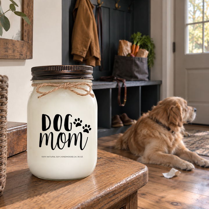 KINDMOOSE DOG MOM 16 oz candle in a cottage mudroom with a Golden Retriever resting nearby after its owner returns home with groceries.