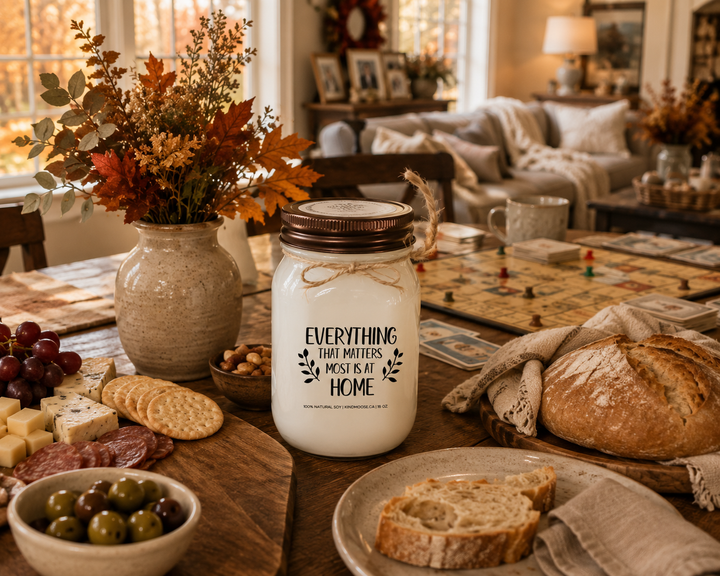 EVERYTHING THAT MATTERS MOST IS AT HOME soy candle with distressed bronze lid styled on a family gathering table with charcuterie, fresh bread, board games, and warm autumn farmhouse décor.