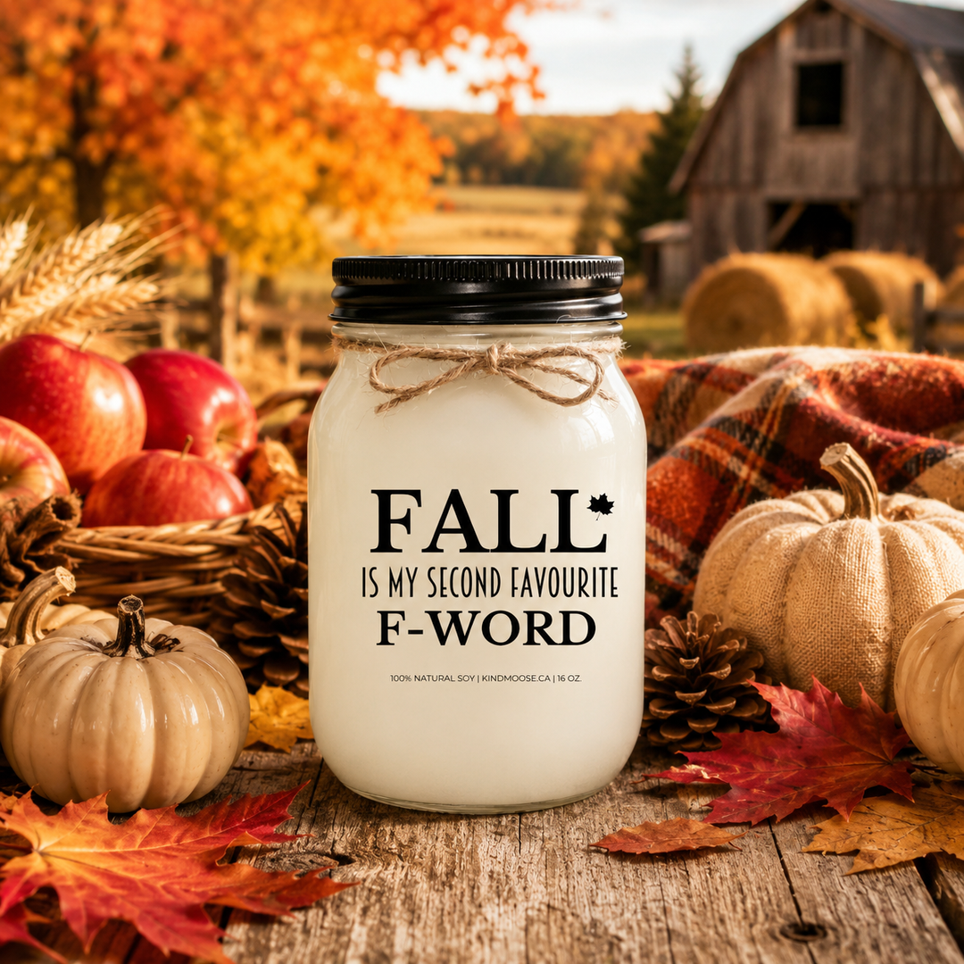 FALL IS MY SECOND FAVOURITE F-WORD soy candle displayed on a rustic harvest table with pumpkins, apples, colourful autumn leaves, pinecones, wheat stems, and cozy fall farmhouse décor.