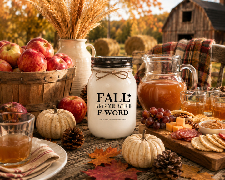 FALL IS MY SECOND FAVOURITE F-WORD soy candle with distressed bronze lid styled on a farmhouse table with apple cider, fresh apples, pumpkins, pinecones, seasonal snacks, and autumn harvest décor.