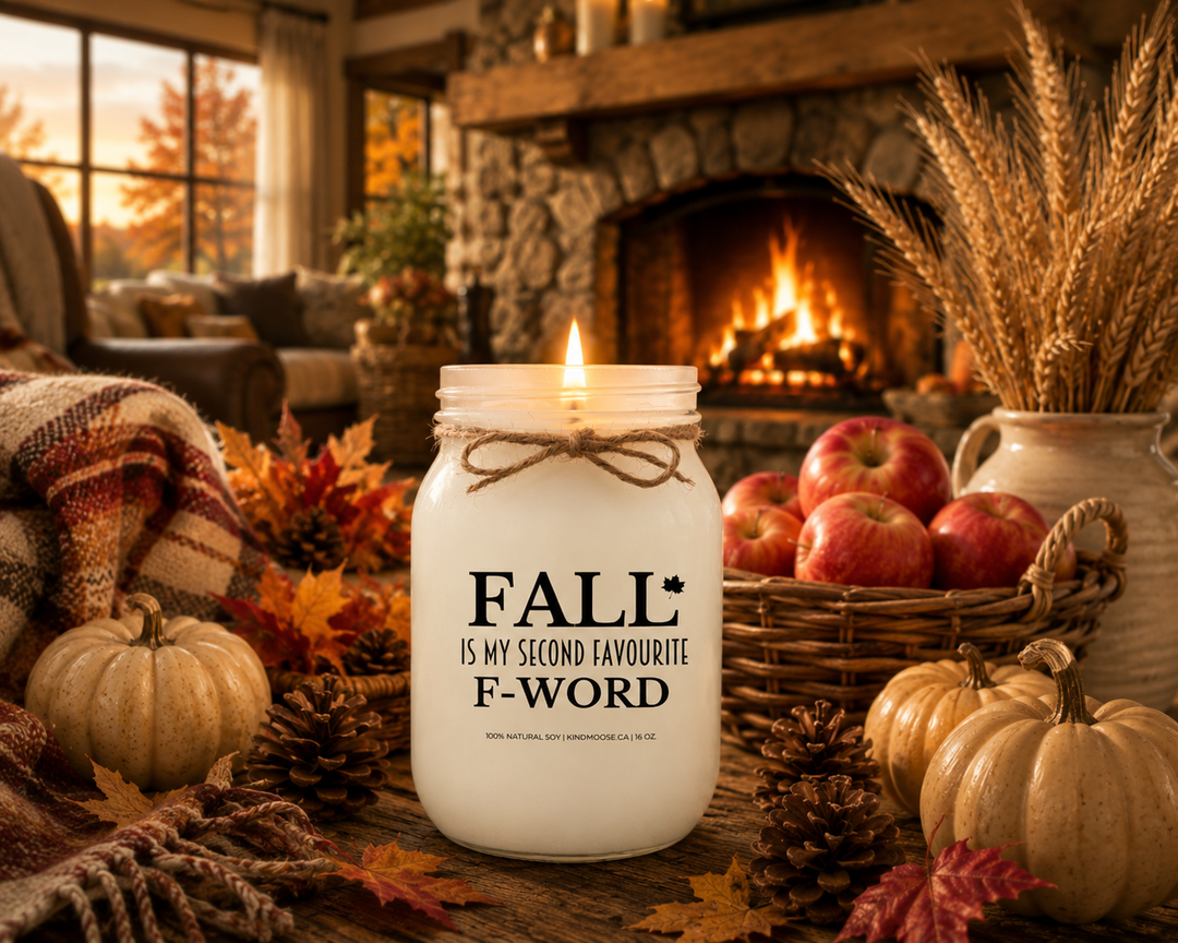 Burning FALL IS MY SECOND FAVOURITE F-WORD soy candle in a cozy farmhouse living room with a stone fireplace, plaid blanket, pumpkins, apples, autumn leaves, and warm fall evening atmosphere.