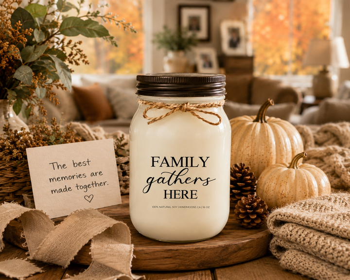 FAMILY GATHERS HERE soy candle with distressed bronze lid styled as a thoughtful family-inspired gift on a farmhouse entry table. Surrounded by neutral pumpkins, pinecones, autumn greenery, linen ribbon, woven textures, and a handwritten card reading “The best memories are made together,” the scene celebrates home, family, and meaningful connections.