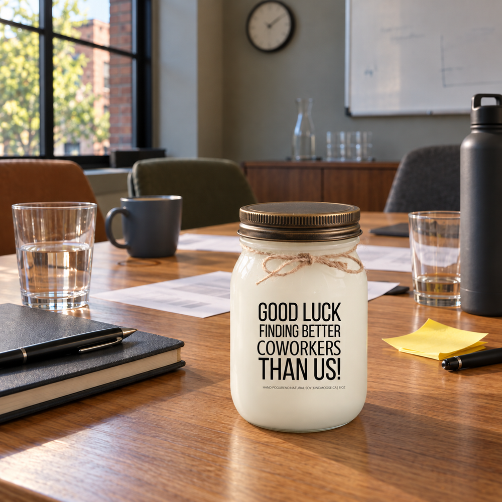 KINDMOOSE Good Luck Finding Better Coworkers Than Us candle with distressed bronze lid on a meeting room table after a coworker meeting.