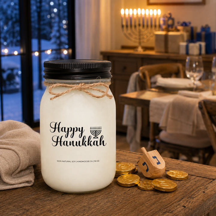 KINDMOOSE Happy Hanukkah 16 oz candle with black lid in a warm family home with menorah, dreidel and Hanukkah gifts.