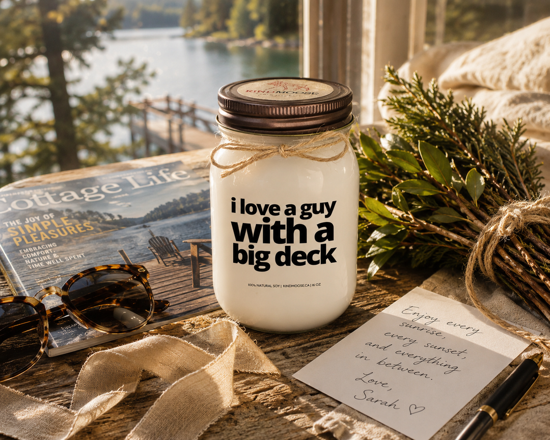 I Love A Guy With A Big Deck candle with distressed bronze lid styled as a thoughtful cottage gift beside a handwritten note, linen ribbon, greenery, sunglasses, and cottage magazine on a rustic wood table.