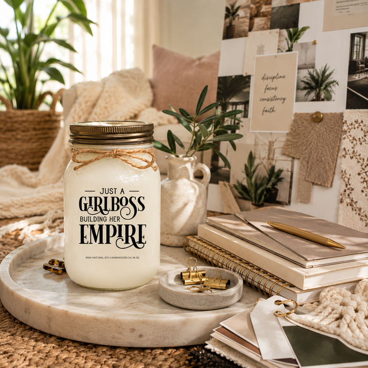 KINDMOOSE Just A Girlboss Building Her Empire soy candle in a creative design studio surrounded by fabric swatches, branding materials and a modern entrepreneur's workspace.