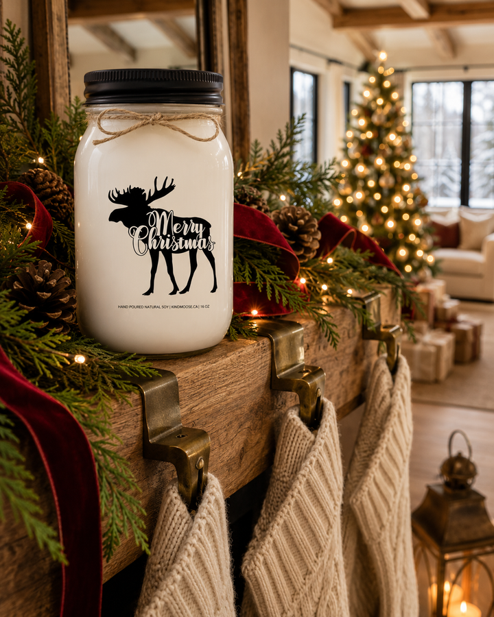 Merry Christmas personalized soy candle with a black lid displayed on a rustic white oak fireplace mantel decorated with cedar garland, warm Christmas lights, pinecones, cream knit stockings, and a softly glowing Christmas tree in a luxury farmhouse living room.