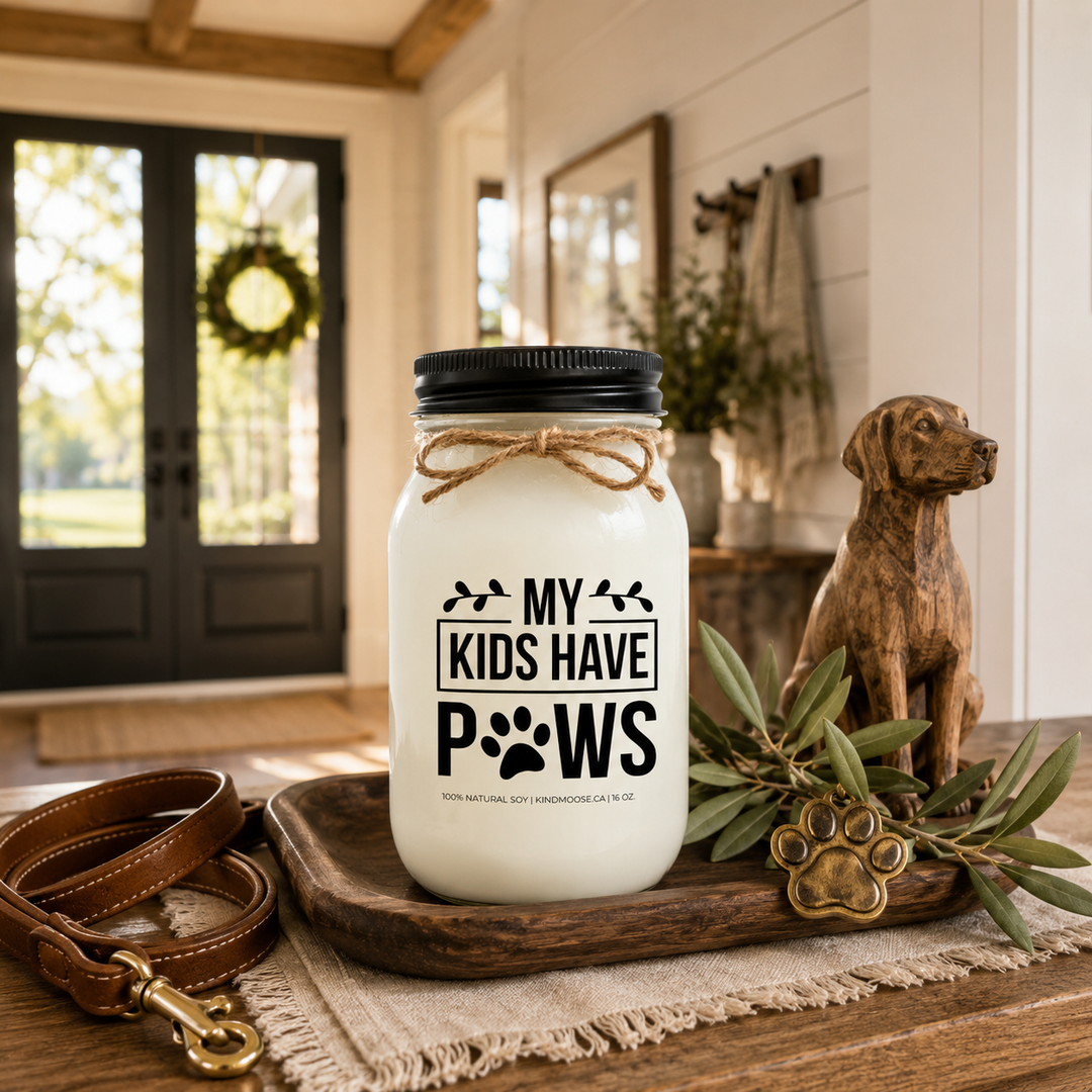 My Kids Have Paws customizable 16 oz soy candle with a black lid displayed on a reclaimed white oak entryway console beside a leather dog leash, walnut tray, brass paw ornament, and olive branches. Bright morning sunlight fills a luxury modern farmhouse foyer celebrating the unconditional love of pets.