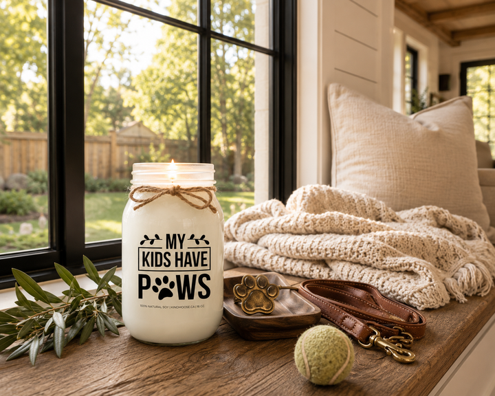 My Kids Have Paws customizable 16 oz soy candle burning on a reclaimed white oak window seat beside a cream knit throw, linen cushion, leather dog leash, brass paw ornament, and tennis ball. Golden afternoon sunlight fills a peaceful modern farmhouse reading nook overlooking a tree-lined backyard.