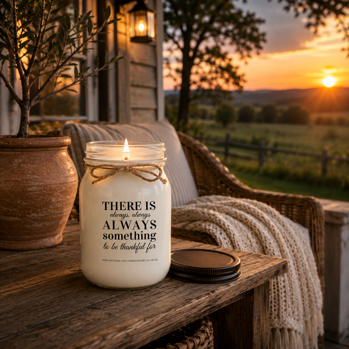 Burning KINDMOOSE "There Is Always Something to Be Thankful For" 16 oz natural soy candle at sunset on a cozy farmhouse porch, creating a warm and peaceful evening atmosphere.
