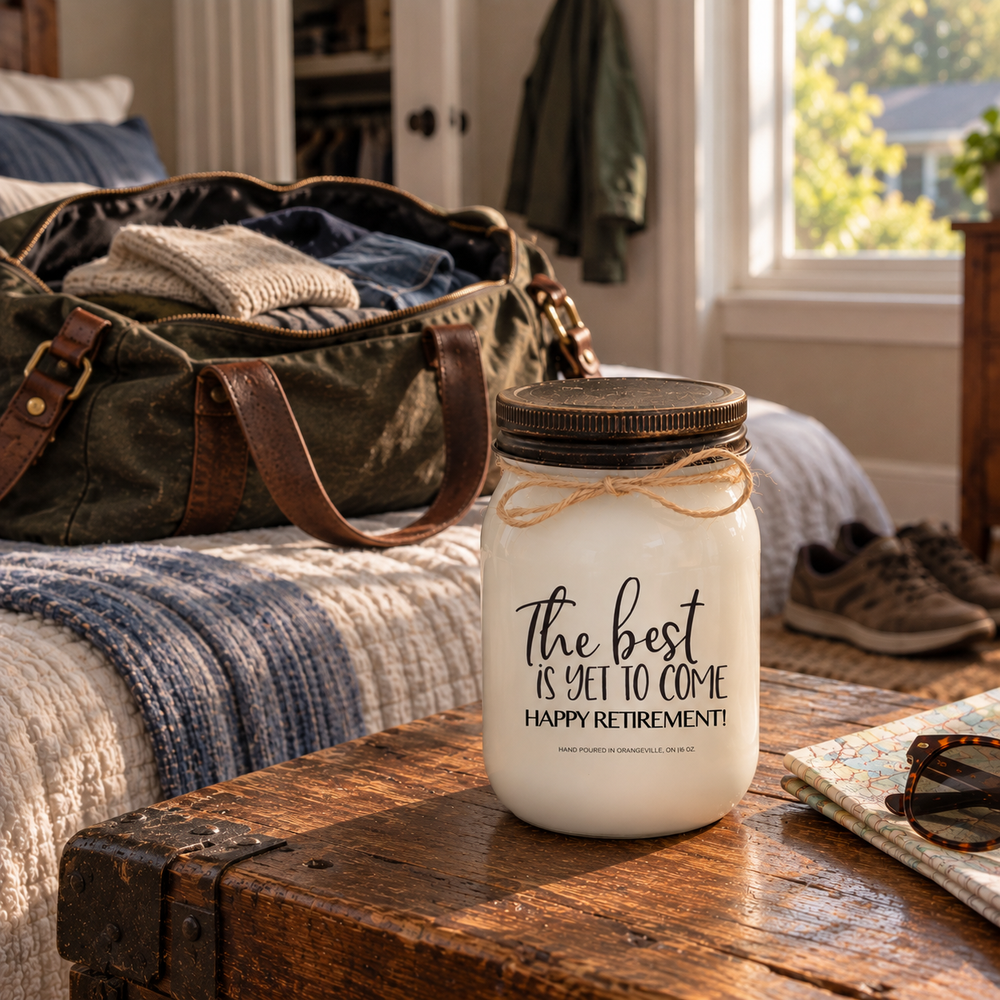 The Best Is Yet to Come Happy Retirement KINDMOOSE candle beside an open weekender bag, capturing the freedom to travel after retirement.