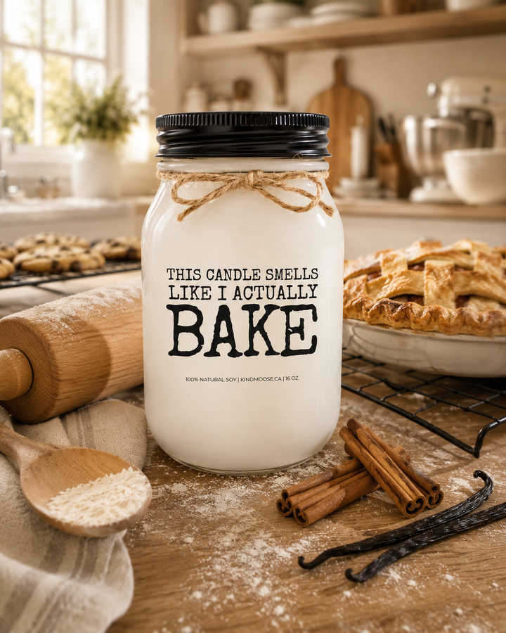 THIS CANDLE SMELLS LIKE I ACTUALLY BAKE soy candle displayed on a rustic farmhouse kitchen island surrounded by a freshly baked pie, cinnamon sticks, vanilla beans, and warm wood accents. Bathed in natural sunlight, the inviting hero image captures the comforting aroma and cozy charm of a home that always smells like fresh baking.